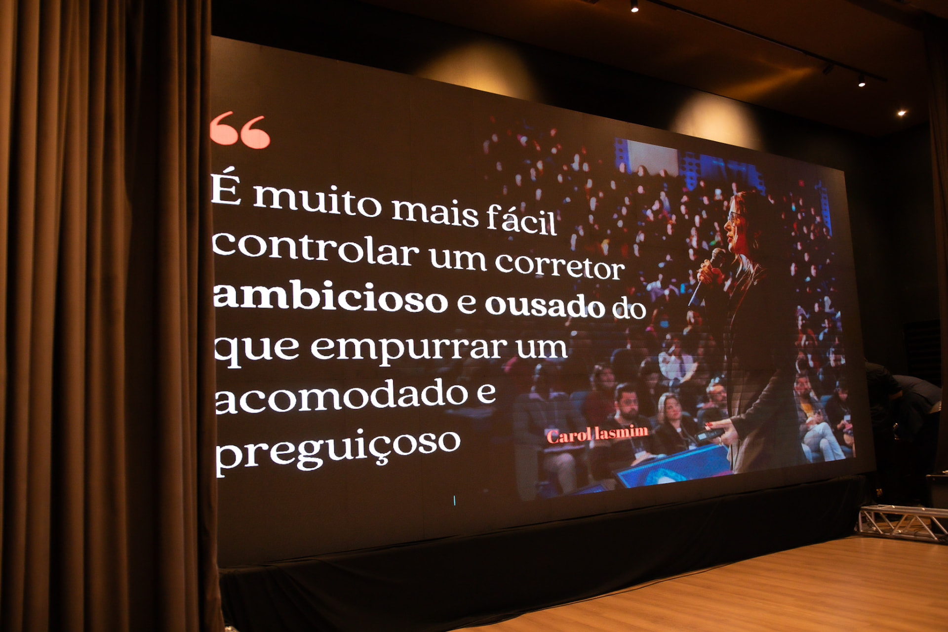 Telão do evento exibindo citação de palestrante sobre gestão de corretores