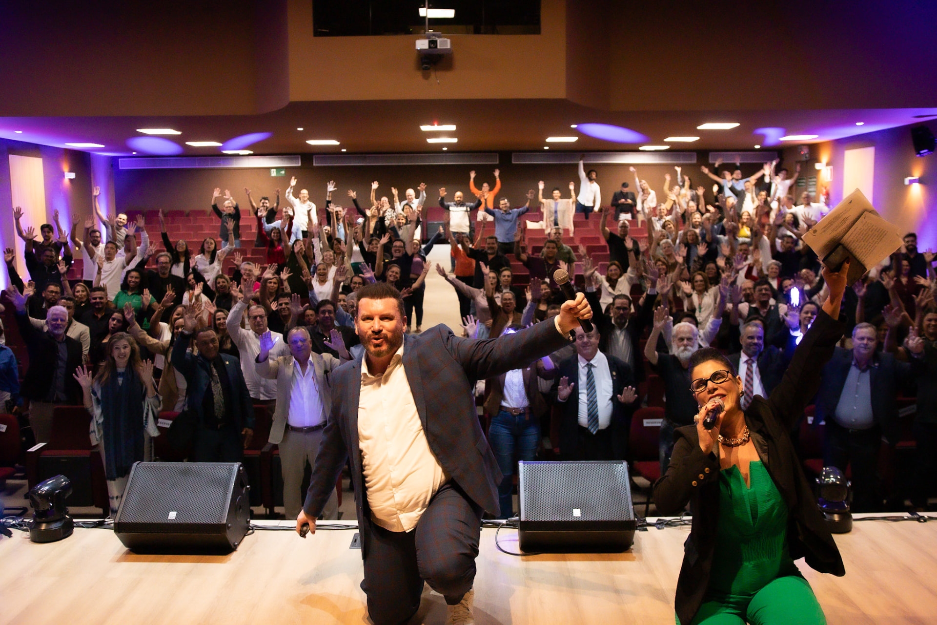 Plateia do MinasImob Experience de pé com as mãos levantadas ao final de uma palestra