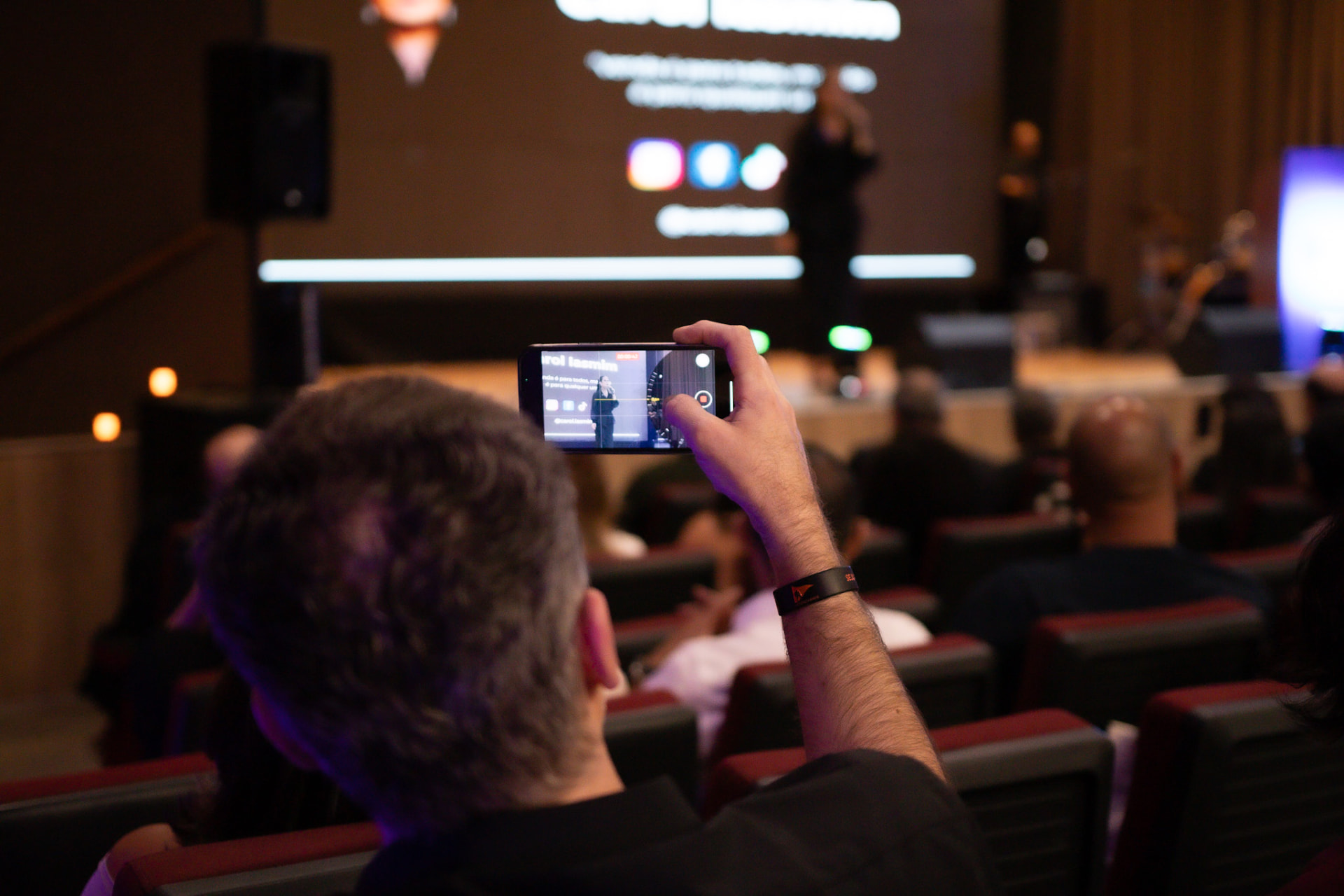 Participante gravando a palestra com o celular durante o evento